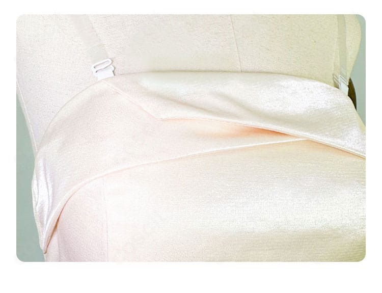 首元の領口と肩帯装飾ディテール。白の質感と縫製、透明ストラップの取り付け位置が見える接写。